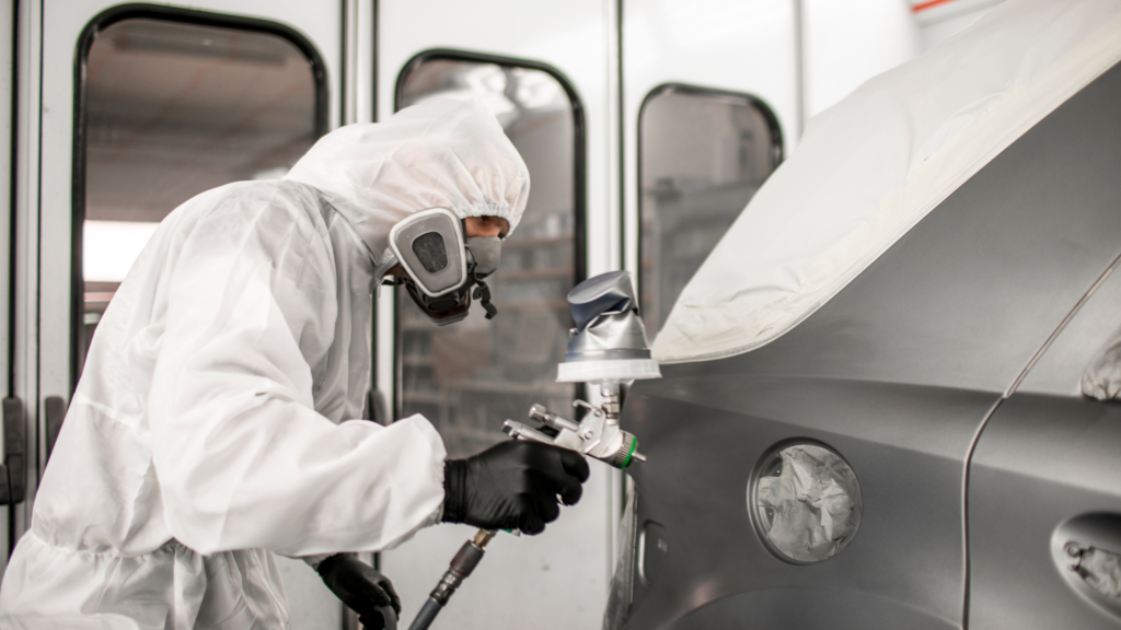 Man in white suit spray painting car